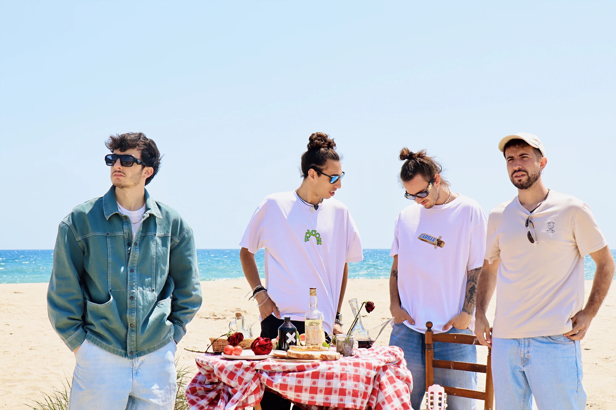 Els quatre membres de Banda Neon al voltant d’una taula davant del mar
